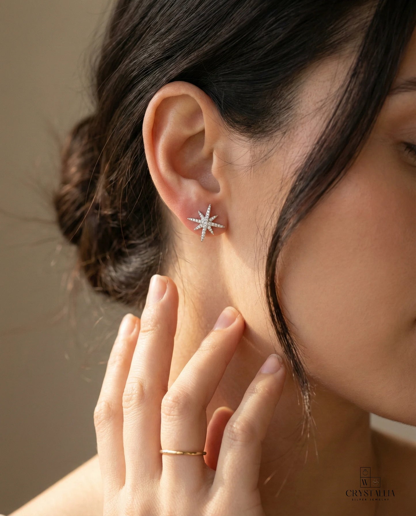 אישה בת 23 לובשת עגילי כסף טהור מבית קריסטליה, המציגים גימור מלוטש ועיצוב יוקרתי המתאים לכל סגנון לבוש.