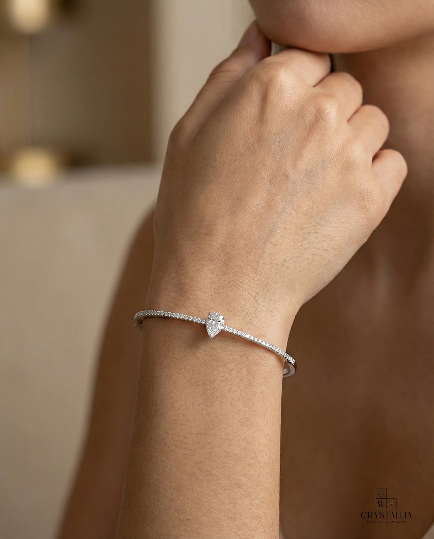 דוגמנית עם צמיד קשיח יוקרתי של מותג קריסטליה, עשוי כסף אמיתי 925 ומשובץ בשורת אבני קריסטל מנצנצות לאורכו.