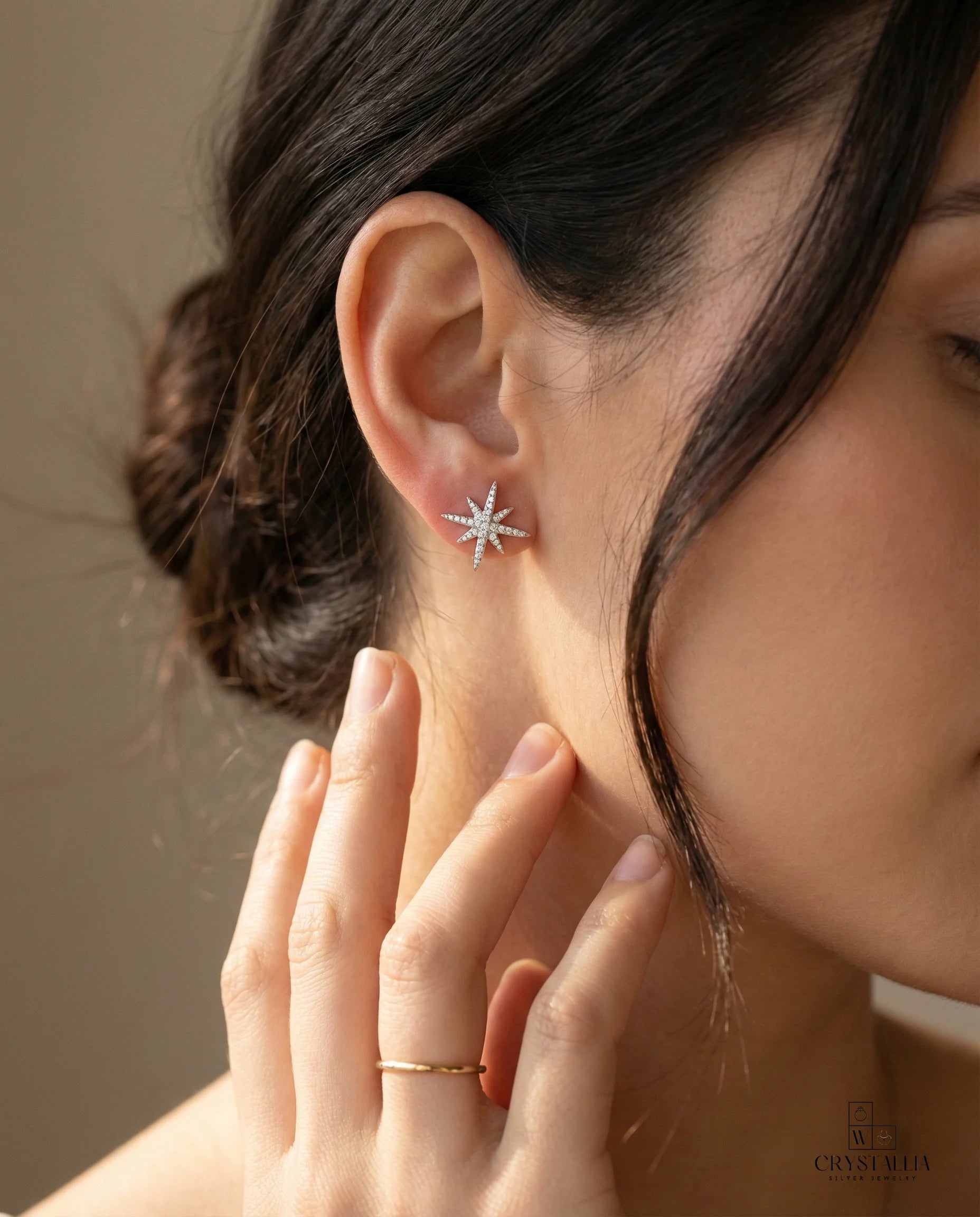 אישה בת 23 לובשת עגילי כסף טהור מבית קריסטליה, המציגים גימור מלוטש ועיצוב יוקרתי המתאים לכל סגנון לבוש.