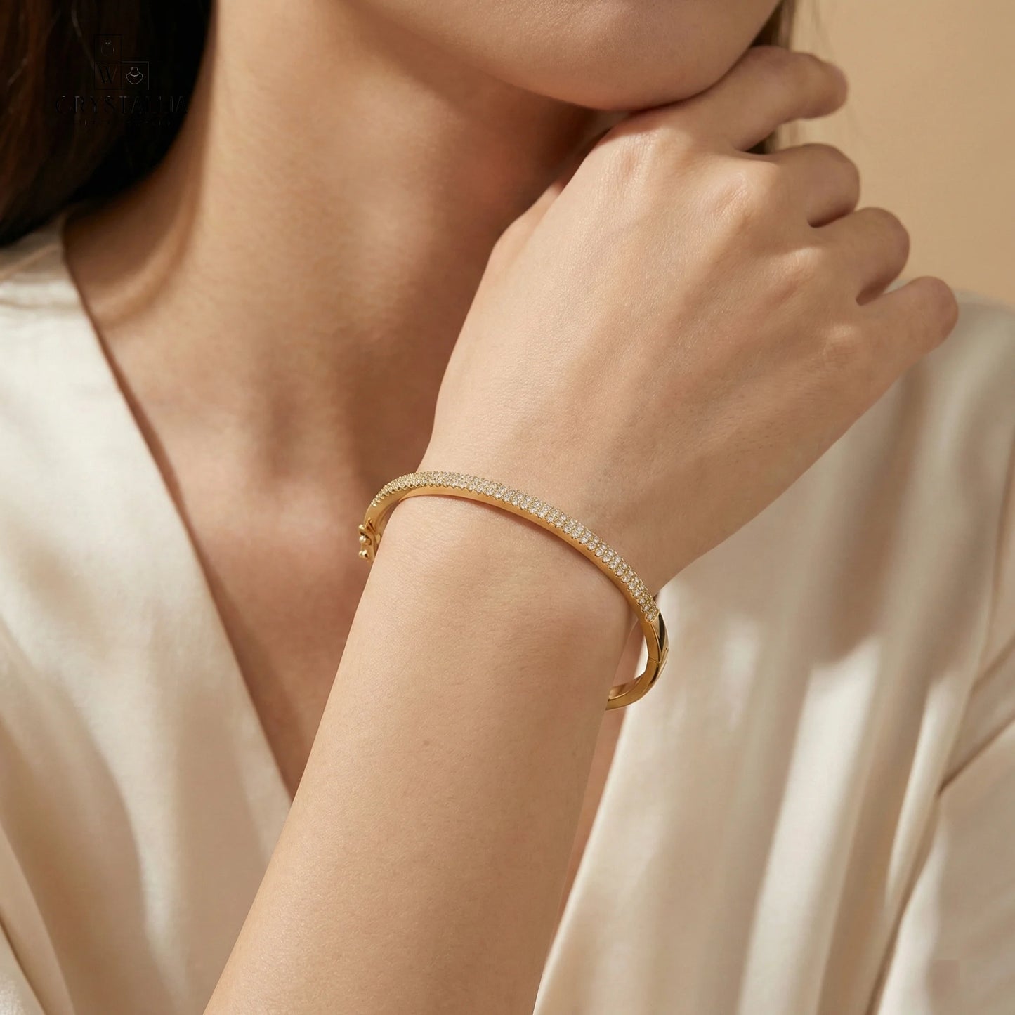 אישה לובשת צמיד קשיח לנשים דגם KSI6013-3 עשוי פליז בציפוי זהב 14K איכותי בשיבוץ אבני קריסטל מנצנצות לכל אורכו