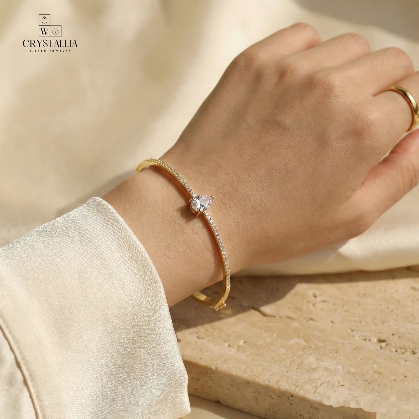 יש של אישה עם צמיד קשיח לנשים דגם עשוי פליז בציפוי זהב 14K עבה (2 מיקרון) משובץ באבני קריסטל מנצנצות על רקע נקי