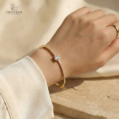 יש של אישה עם צמיד קשיח לנשים דגם עשוי פליז בציפוי זהב 14K עבה (2 מיקרון) משובץ באבני קריסטל מנצנצות על רקע נקי