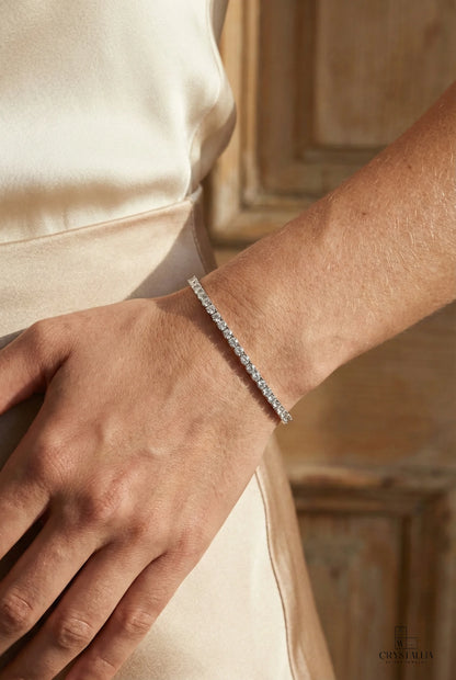 יש של אישה עליה צמיד טניס יוקרתי עשוי כסף סטרלינג 925 ומשובץ בשורת אבני קריסטל באיכות 5A למראה מנצנץ ויוקרתי על פרק כף היד.